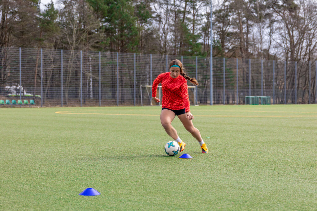 Futbol sahasında çeviklik ve denge antrenmanı yapan bir sporcu.